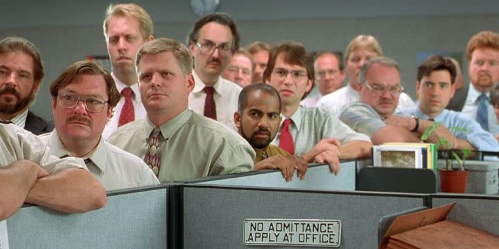 Office employees stand in a meeting in "Office Space."