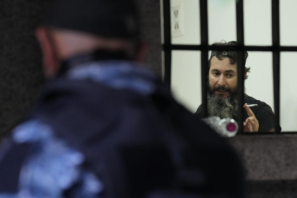 An armed man Bassam al-Sheikh Hussein, 42, right, speaks with one of his hostages inside a bank, in Beirut, Lebanon, Thursday, Aug. 11, 2022. A hostage standoff in which a gunman demanded a Beirut bank let him withdraw his trapped savings so that he could pay his father's medical bills ended seven hours later with the man's surrender Thursday. (AP Photo/Hussein Malla)