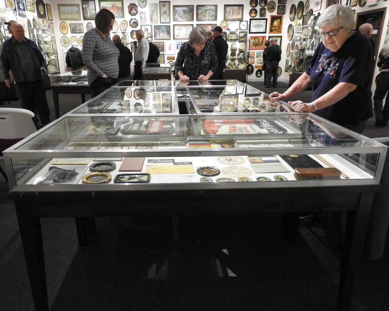 Visitors to the Johnson-Humrickhouse Museum look at specialty advertising items in a case in the second floor special exhibit gallery prior to a presentation on the exhibit by Joe Kreitzer.