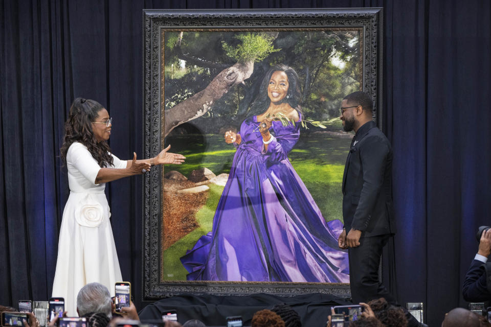 Oprah Winfrey reaches out to hug artist Shawn Michael Warren, right, after they unveiled Warren's portrait of Winfrey, Wednesday, Dec. 13, 2023, during a ceremony at the Smithsonian's National Portrait Gallery in Washington. (AP Photo/Jacquelyn Martin)