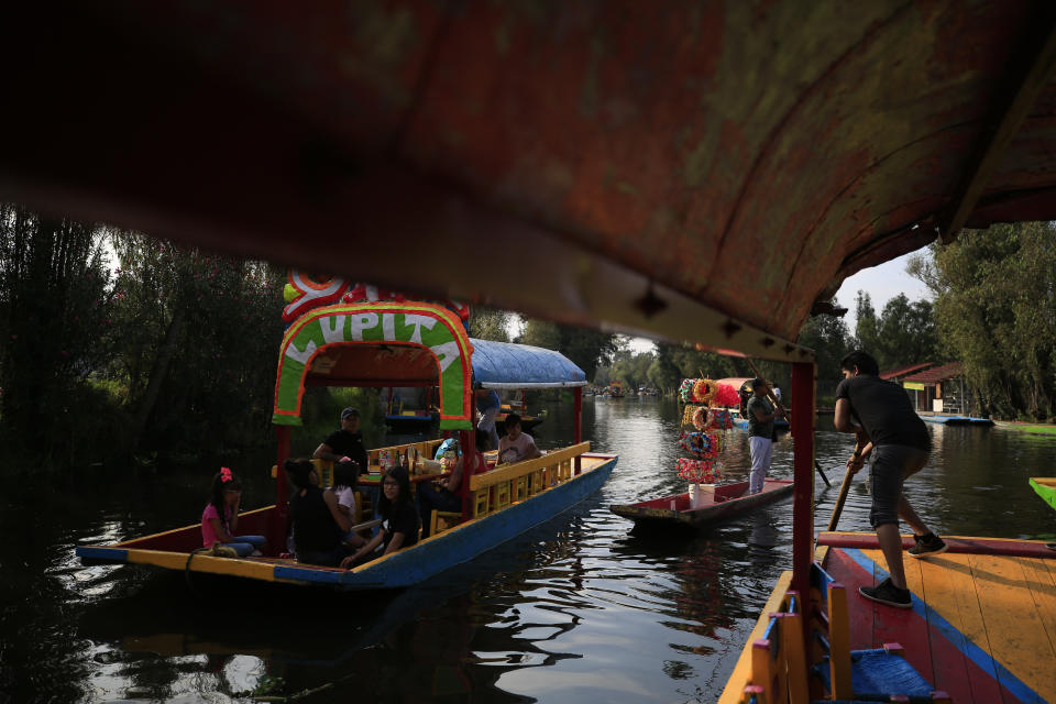 A flower crown vendor plies his wares between two trajineras, colorful passenger boats typically rented by tourists, families, and groups of young people, in Xochimilco, Mexico City, Friday, Sept. 6, 2019. The usually festive Nativitas pier was subdued and largely empty Friday afternoon, with some boat operators and vendors estimating that business was down by 80% on the first weekend following the drowning death of a youth that was captured on cellphone video and seen widely in Mexico. Borough officials stood on the pier to inform visitors of new regulations that went into effect Friday limiting the consumption of alcohol, prohibiting the use of speakers and instructing visitors to remain seated.(AP Photo/Rebecca Blackwell)