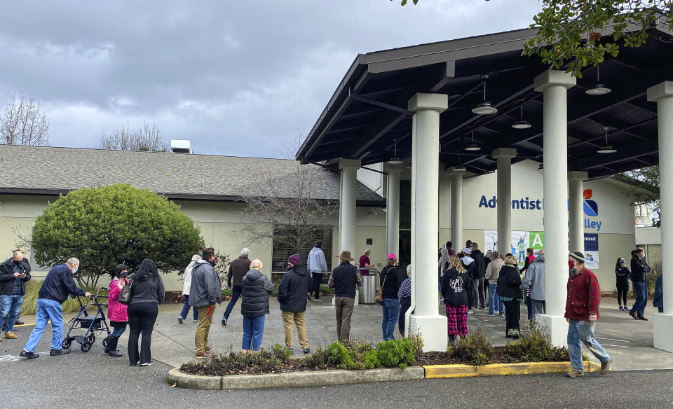 In this photo provided by The Mendocino Voice, people line up outside the Adventist Health Ukiah Valley Medical Center, Monday, Jan. 4, 2021, in Ukiah, Calif., to get the Moderna COVID-19 vaccination during an emergency vaccine drive. A power failure for the freezer holding the county's ration of the Moderna vaccines forced the emergency distribution of 850 doses of that vaccine. (Jethro Bowers/The Mendocino Voice via AP)
