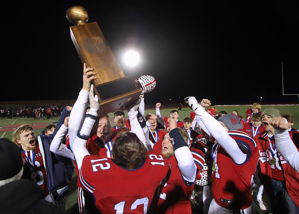 West Central players hoist the Illinois 8-player championship trophy after winning 44-36 against Amboy Friday in Monmouth, Illinois.