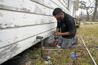 West Street Recovery's Johnny Vicar works to repair busted pipes under a home, that were frozen during the recent winter storm, Thursday, Feb. 25, 2021, in Houston. West Street Recovery, a nonprofit created in the wake of Hurricane Harvey to help repair flood damaged homes, has been working since the winter storm hit to repair and replace damaged plumbing systems for residents who can't afford to do so. (AP Photo/David J. Phillip)