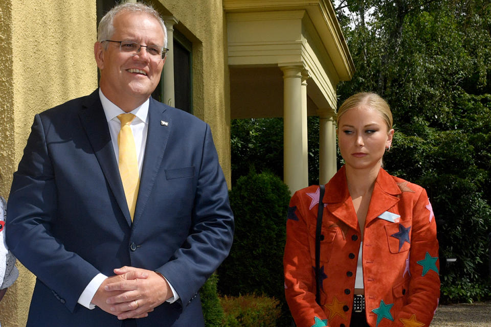 Prime Minister Scott Morrison smiles as 2021 Australian of the Year Grace Tame looks at the ground.