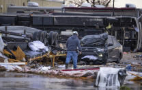 A man walks through a parking lot containing multiple overturned vehicles, including a trailer that was in a parking lot across the street, according to people at the scene, where a tornado was reported to pass along Mickey Gilley Boulevard near Fairmont Parkway, Tuesday, Jan. 24, 2023, in Pasadena, Texas. (Mark Mulligan/Houston Chronicle via AP)