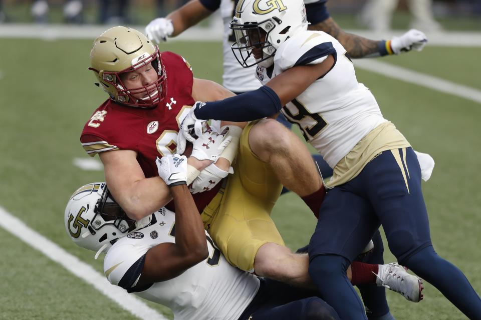 Georgia Tech defensive backs Tre Swilling, bottom, and Wesley Walker, right, tackle Boston College tight end Hunter Long during the first half of an NCAA college football game Saturday, Oct. 24, 2020, in Boston. (AP Photo/Michael Dwyer)