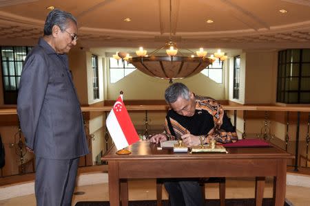 Singapore's Prime Minister Lee Hsien Loong signs a guestbook next to Malaysia's Prime Minister Mahathir Mohamad prior to their private meeting at the Perdana Leadership Foundation in Putrajaya, Malaysia May 19, 2018. Department of Information/Hafiz Itam via REUTERS