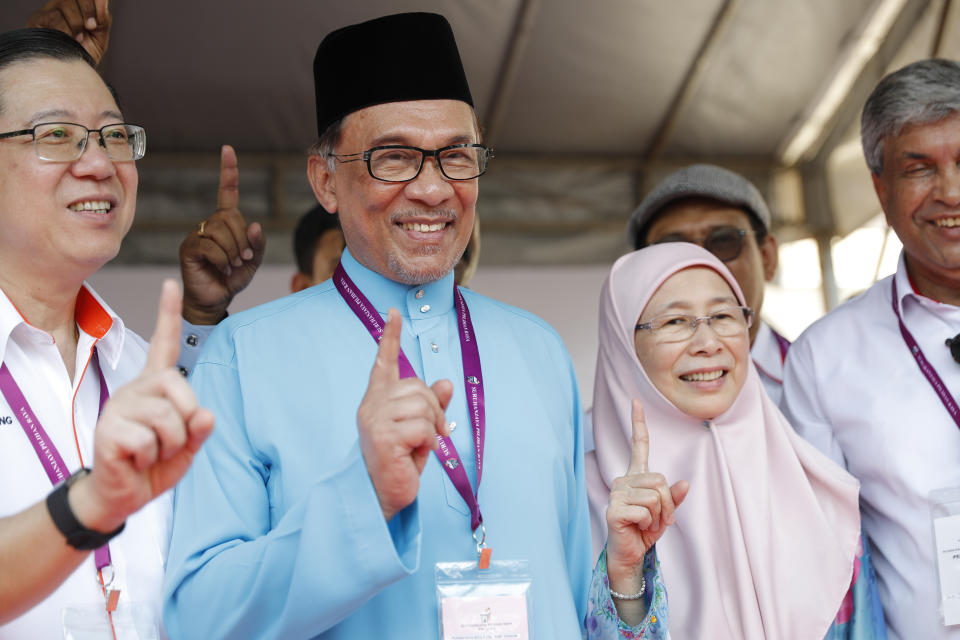 Malaysia's reform icon, Anwar Ibrahim, center, with his wife Deputy Prime Minister Wan Azizah show No.1 sign for by-election nomination in Port Dickson, Malaysia, Saturday, Sept. 29, 2018. Anwar is contesting The Oct. 13 by-election in Port Dickson, a southern coastal town after a lawmaker vacated the seat to make way for Anwar Ibrahim's political comeback. (AP Photo/Vincent Thian)