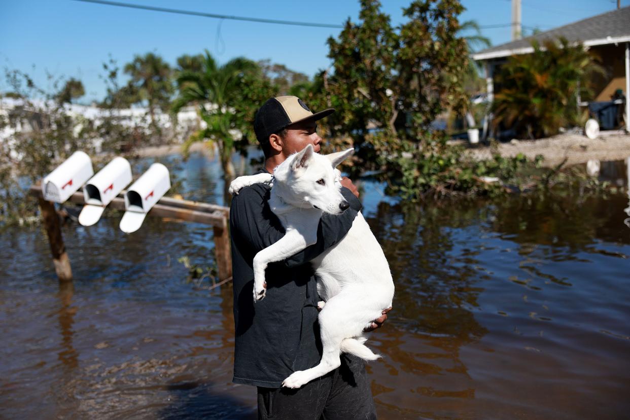 Jordan Reidy carries his dog, Ivory,  back to their second-floor apartment after fleeing when Hurricane Ian passed through the area on September 30, 2022 in Fort Myers, Florida. 