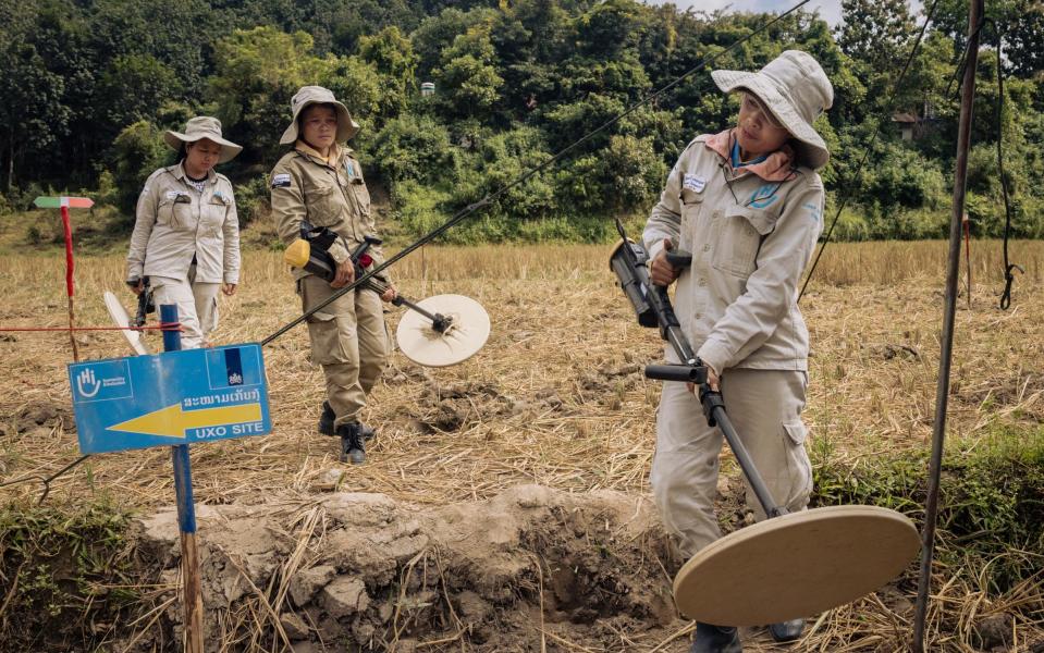 Instead of sickles, the women are carrying heavy metal detectors, scanning for UXO