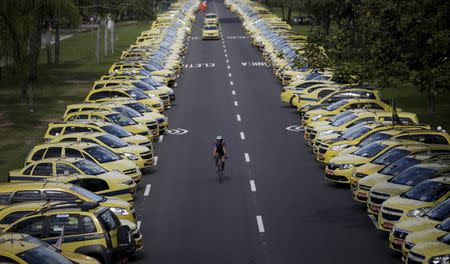 A man rides his bicycle between taxis parked on the street during a protest against the online car-sharing service Uber in Rio de Janeiro, Brazil July 24, 2015. REUTERS/Ricardo Moraes TPX IMAGES OF THE DAY