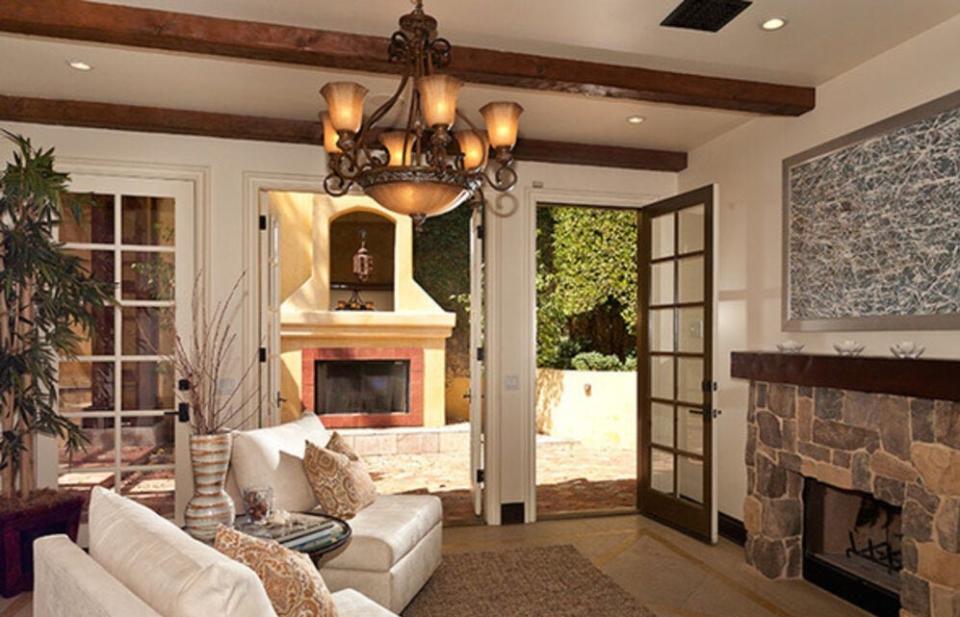 The step-down living room with beamed ceiling and fireplace. The pictures were taken by the listing agent before the "squatters" moved in.