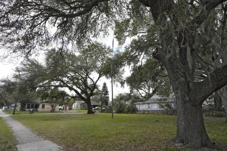 A cyclist stops to look at the scene of a shooting Tuesday, Jan. 31, 2023, in Lakeland, Fla. Police say several people were shot and wounded during a drive-by shooting in a central Florida neighborhood. (AP Photo/Chris O'Meara)