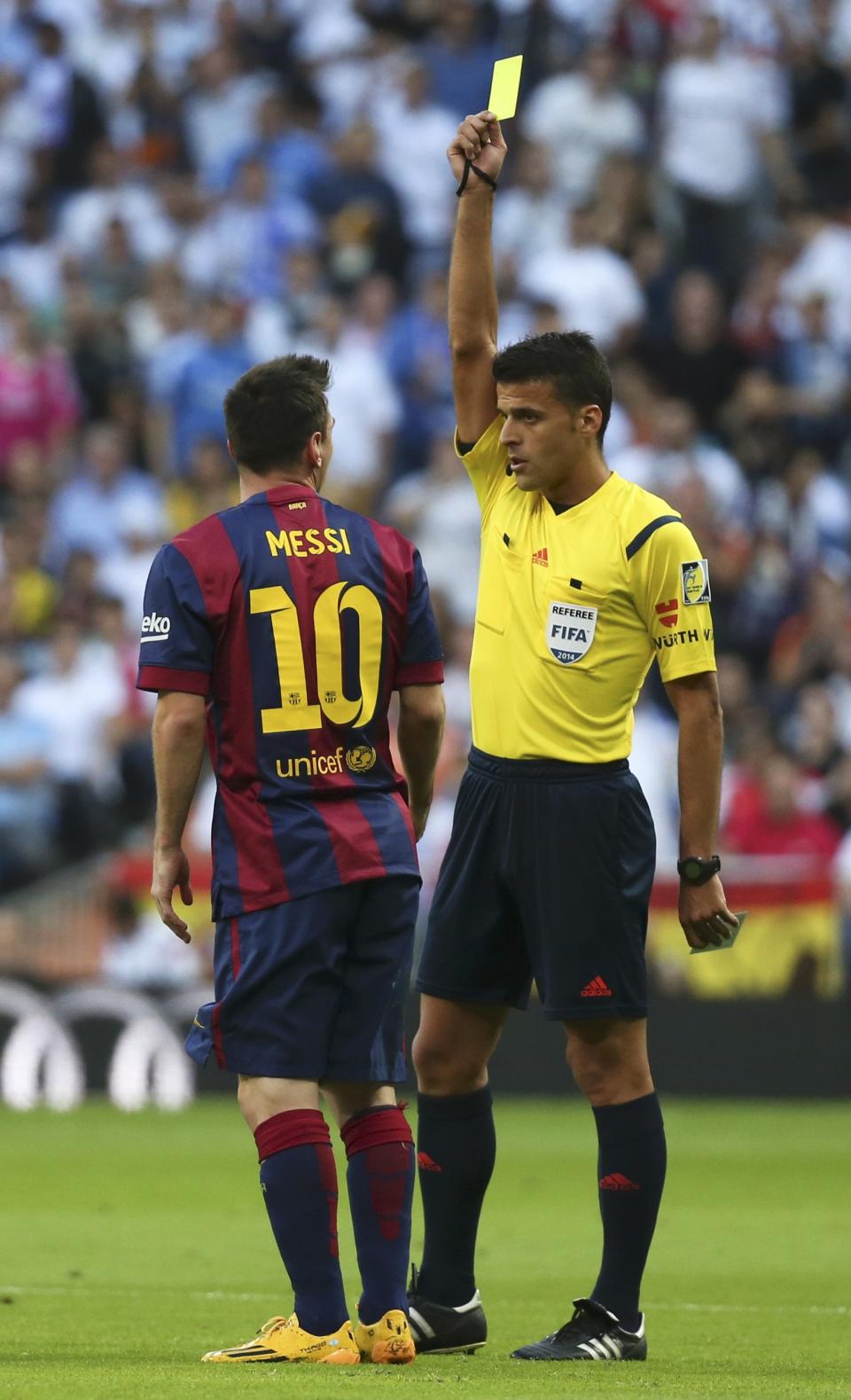 Barcelona's Lionel Messi (L) is shown a yellow card by referee Gil Manzano during the Spanish first division "Clasico" soccer match against Real Madrid at the Santiago Bernabeu stadium in Madrid October 25, 2014. REUTERS/Stringer (SPAIN - Tags: SOCCER SPORT)