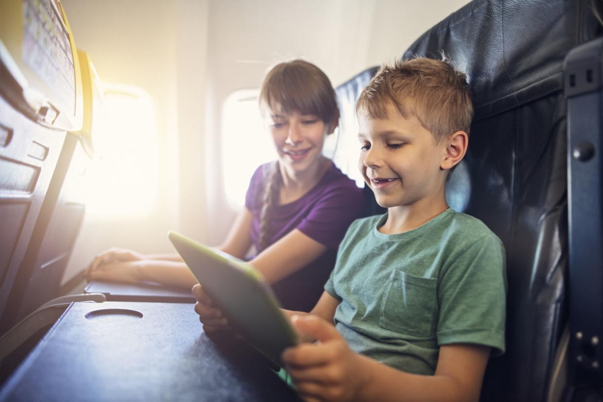 Kids sitting in the plane and playing with tablet. The boy is aged 7 and the girl is 10.Shot with Nikon D810