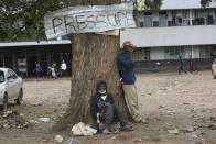 Two men relax under a tree in a poor township on the outskirts of the capital Harare, Tuesday, Nov, 16, 2021. When the coronavirus first emerged last year, health officials feared the pandemic would sweep across Africa, killing millions and destroying the continent’s fragile health systems. Although it’s still unclear what COVID-19’s ultimate toll will be, that catastrophic scenario has yet to materialize in Zimbabwe or much of Africa. (AP Photo/Tsvangirayi Mukwazhi)