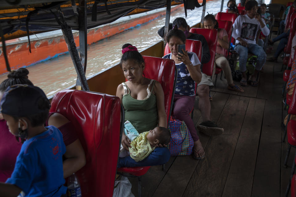 Amazonian residents wait for a public boat to leave the Pucallpa port, in Peru's Ucayali region, Monday, Oct. 4, 2020. The Ucayali region located along a muddy river has long seen periodic dengue outbreaks, though this year's figures are already three times that seen in 2019. In the city of Pucallpa, doctors say they are beginning to encounter patients with the double diagnosis of COVID-19 and dengue. (AP Photo/Rodrigo Abd)