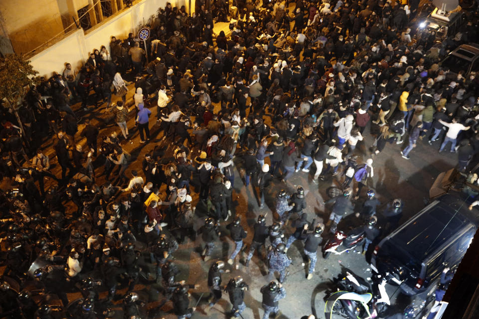 Riot police run behind anti-government protesters who are protesting outside a police headquarters demanding the release of those taken into custody the night before, outside a police headquarter, in Beirut, Lebanon, Wednesday, Jan. 15, 2020. Lebanese security forces arrested 59 people, the police said Wednesday, following clashes overnight outside the central bank as angry protesters vented their fury against the country's ruling elite and the worsening financial crisis. (AP Photo/Hussein Malla)