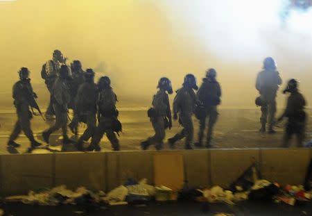 Riot police walk in between tear gas to disperse protesters after thousands of protesters blocked the main street to the financial Central district outside the government headquarters in Hong Kong September 28, 2014. REUTERS/Stringer