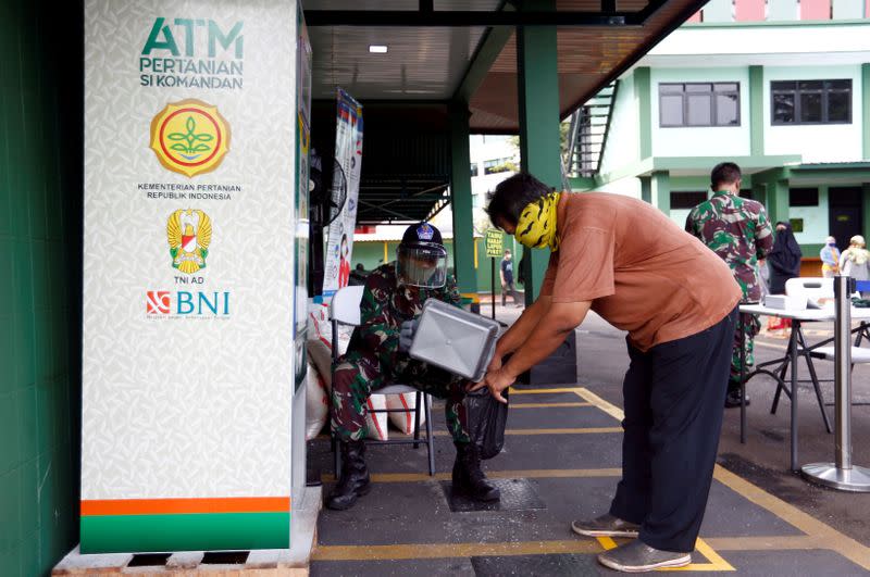 FILE PHOTO: A man wears protective face mask while receiving rice from an automated rice ATM distributor amid the spread of the coronavirus disease (COVID-19) in Jakarta