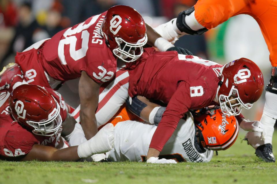 OU's Isaiah Coe (94), R Mason Thomas (32) and Jonah Laulu (8) bring down OSU's Ollie Gordon (0) during the Sooners' 28-13 win in Norman on Nov. 19, 2022.