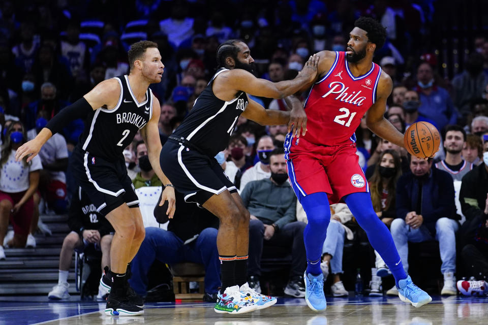 Philadelphia 76ers' Joel Embiid, right, tries to get past Brooklyn Nets' James Harden, center, and Blake Griffin during the first half of an NBA basketball game, Friday, Oct. 22, 2021, in Philadelphia. (AP Photo/Matt Slocum)