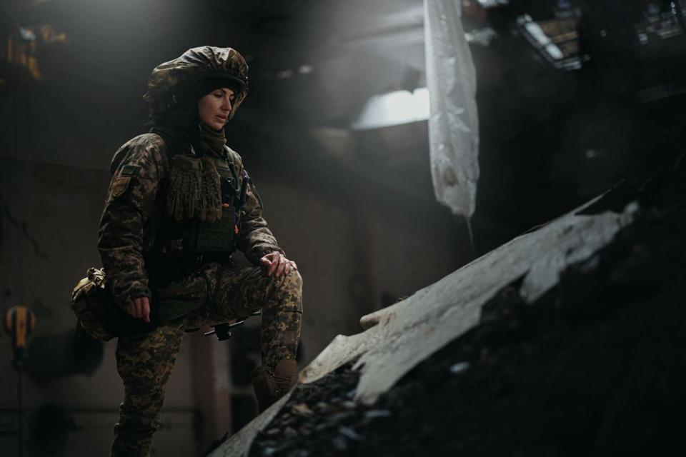 Junior Lieutenant mortar platoon commander Olga Bigar of the Ukrainian Territorial Defense Forces, callsign "Witch,” seen in uniform with one foot on a slab of broken concrete inside a partially ruined building.
