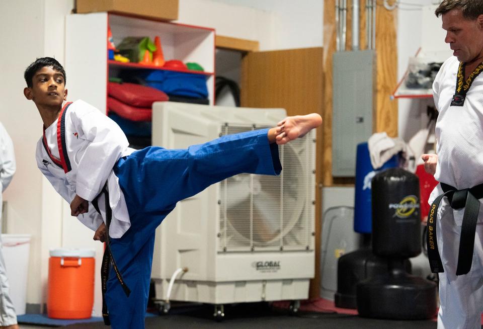 Avinav Prem Anand trains at Polaris Taekwondo recently while head instructor Doug Baker observes. The fifth-grader, who received his black belt in October and who has dozens of martial arts medals, will be competing in the Scripps National Spelling Bee.