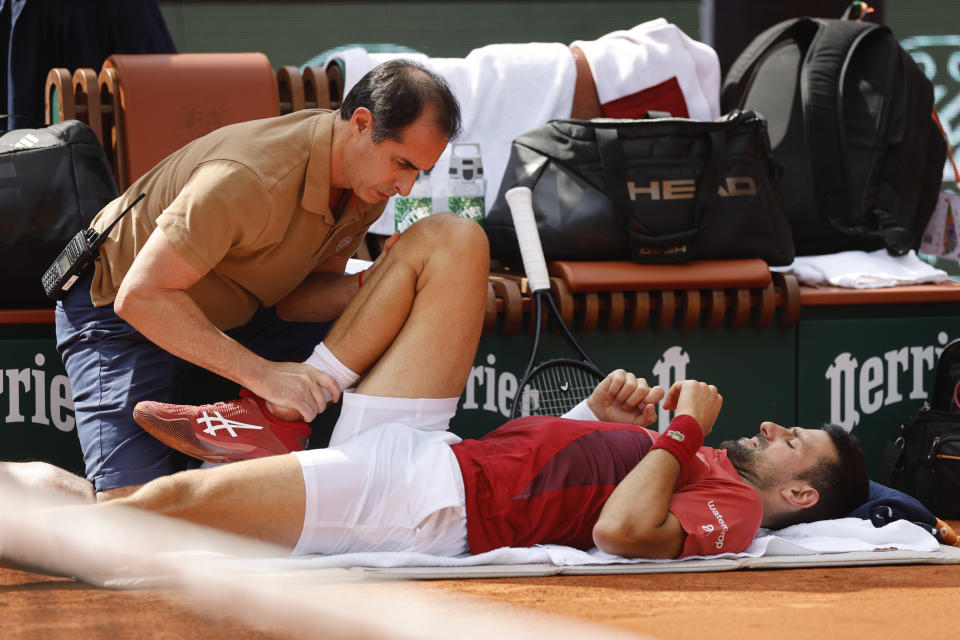 Novak Djokovic recibe asistencia médica en su rodilla derecha durante el partido contra Francisco Cerúndolo en los octavos de final del Abierto de Francia, el lunes 3 de junio de 2024. (AP Foto/Jean-Francois Badias)