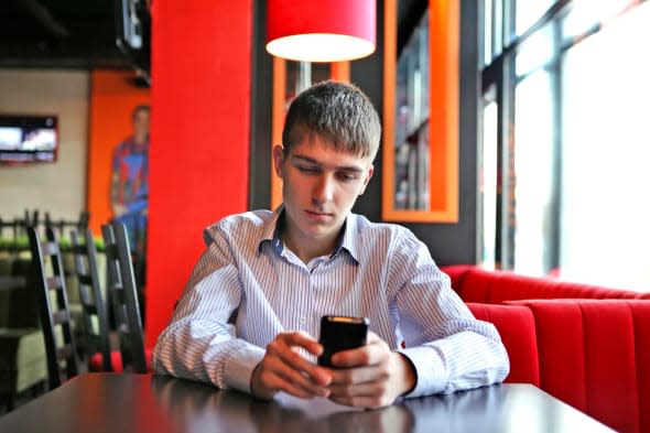 Sad Young Man with Mobile Phone at the table