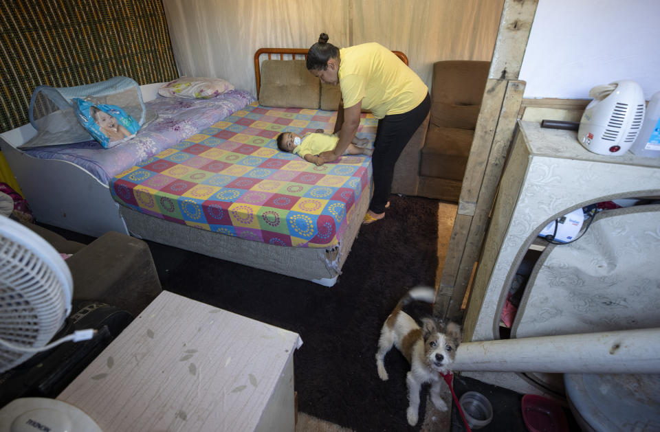 Karina Valdo changes her son's diaper inside her shack in the Jardim Julieta squatter camp in Sao Paulo, Brazil, Thursday, July 23, 2020. The coronavirus had just hit the city when this parking lot for trucks became a favela, with dozens of shacks. Since the first wave of residents in mid-March, hundreds of families joined, with most having been evicted during the pandemic. (AP Photo/Andre Penner)