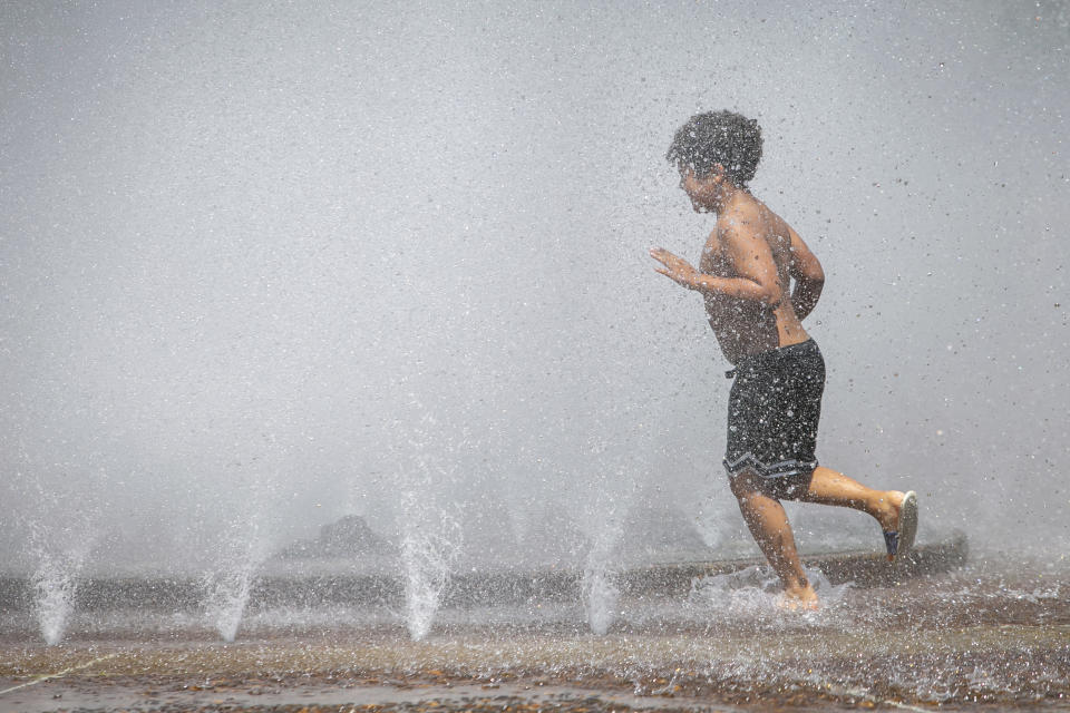 A child cools off in the Salmon Street Springs fountain in downtown Portland, Ore., as a spring heat wave sweeps across the metro area, Saturday, May 13, 2023. (Sean Meagher/The Oregonian via AP)