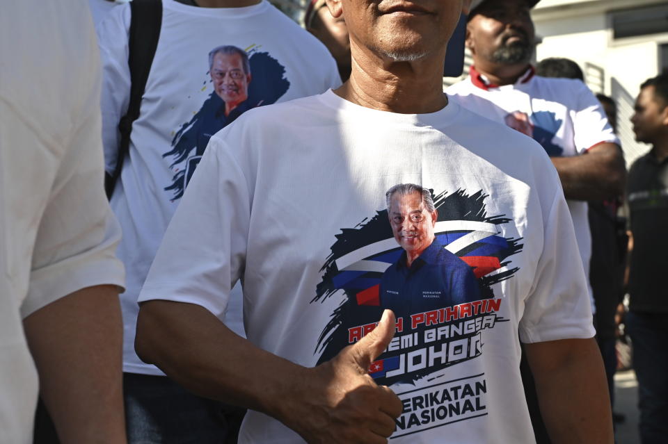 Supporters of former Prime Minister Muhyiddin Yassin show a T shirt with his picture outside the Anti-Corruption Commission headquarters in Putrajaya, Malaysia, Thursday, March 9, 2023. Muhyiddin arrived Thursday at the anti-graft agency office for a second time in a month over alleged corruption in the award of government projects under his rule. (AP Photo)
