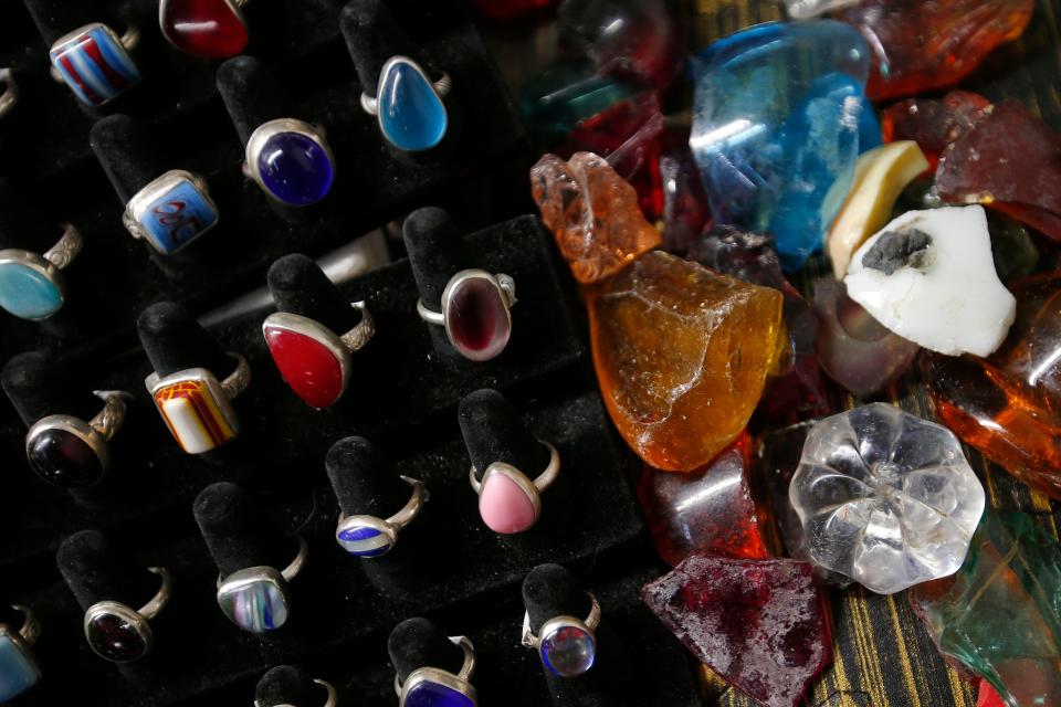 Some of the different rings made by Beth Kirk using recycled broken glass from the Pairpoint Mill fire of 1965. To the right of the photo is some raw glass she plans on making new items with.