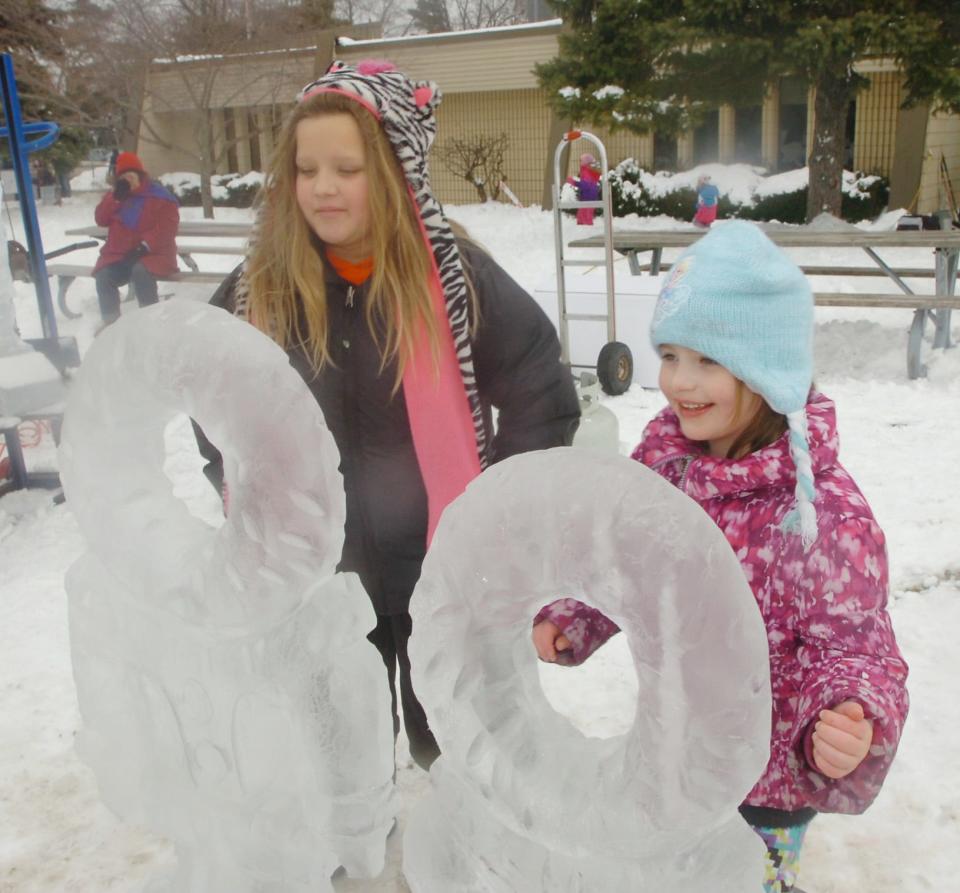 Sisters Madelyn Johnson, 9, left, and Caroline, 6, from Berkley get up close with an ice sculpture at Berkley WinterFest.