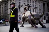 Security guard wearing a face mask walks past the Bund Financial Bull statue on The Bund in Shanghai