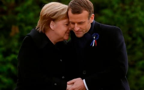 French President Emmanuel Macron and German Chancellor Angela Merkel hug after unveiling a plaque in a French-German ceremony in the clearing of Rethondes (the Glade of the Armistice) in Compiegne - Credit: AFP