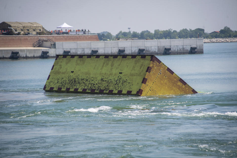 Moveable flood gates rise from the sea in the Venice lagoon, Italy, Friday, July 10, 2020. Venice has conducted a trial run an ambitious anti-flood system of 78 inflatable barriers in the hopes of protecting the lagoon city from devastating high tides. Premier Giuseppe Conte on Friday at a ceremony in Venice pressed a button that activated compressors to pump air into the bright yellow barriers, which then started rising from the sea to act a kind of a dike-on-demand. (Claudio Furlan/LaPresse via AP)