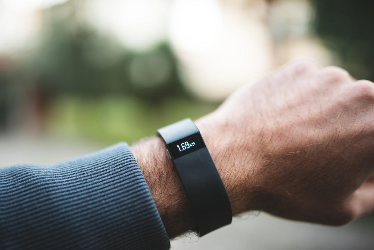 Florence, Italy - January 26, 2014: Close up of the new Fitbit Force on the wrist of a guy. Fitbit Force is the new sport fitness tracker that can allow to track your daily activity, calories burned, sleep & weight, and with that is it possible the upload wirelessly & see progress on mobile and online dashboard. The bracelet is showing the number of daily kms done. image taken outdoor.