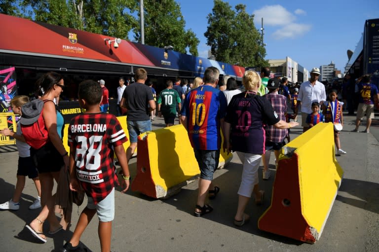 Barcelona fans pass by concrete barriers at the entrance of the Camp Nou stadium on August 20, 2017