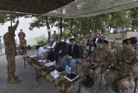 A senior army officer briefs to Pakistani Defense Minister Pervez Khattak, sitting in first row, 1st left, Foreign Minister Shah Mahmood Qureshi, 2nd left, and Moeed Yusuf, the National Security Advisor to the Prime Minister of Pakistan, third left, during their visit to forward area post along a highly militarized frontier in the disputed region of Kashmir, in Chiri Kot sector, Pakistan, Monday, Aug. 3, 2020. The region's top Pakistani military commander briefed ministers about Indian cease-fire violations in Kashmir, which is split between Pakistan and India and claimed by both in its entirety. (AP Photo/Anjum Naveed)