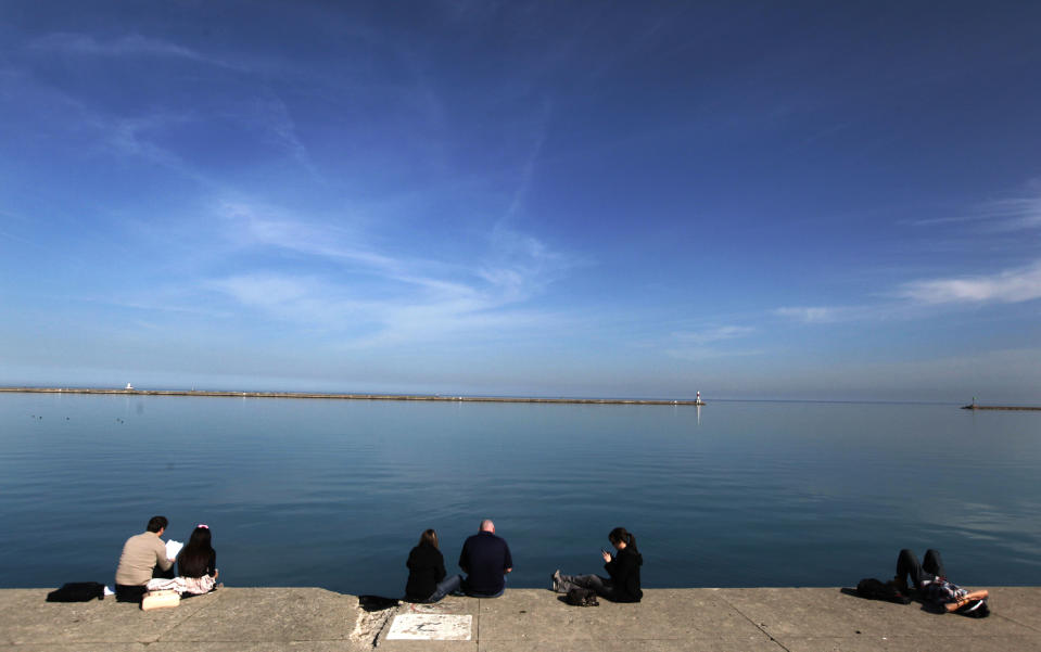 Small groups of people gather on the Lake Michigan waterfront at DuSable Harbor Tuesday, March 13, 2012, in Chicago. Temperatures inch closer to March record highs after a mild winter. (AP Photo/Charles Rex Arbogast)