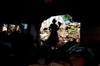 A woman exits her collapsed home in Chimanimani, Zimbabwe, Sunday, March 24 2019. Cyclone Idai's death toll has risen above 750 in the three southern African countries hit 10 days ago by the storm, as workers restore electricity, water and try to prevent outbreak of cholera, authorities said Sunday. (AP Photo/KB Mpofu)
