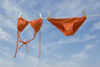 Orange bikini hanging on a clothesline against a blue sky