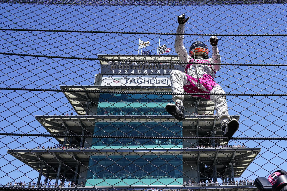 Helio Castroneves of Brazil climbs the fence at the start/finishing as he celebrates after winning the Indianapolis 500 auto race at Indianapolis Motor Speedway in Indianapolis, Monday, May 31, 2021. (AP Photo/Paul Sancya)