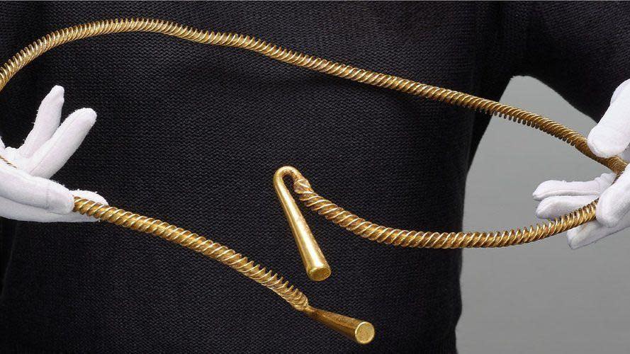 Bronze Age torc found in Cambridgeshire being held by a person wearing white gloves
