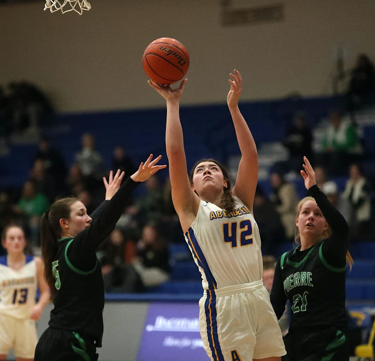 Aberdeen Central's Kiana Mounga (42) goes up for a shot over Pierre's Reese Terwilliger (15) and Ayvrie Kaiser (21) inside Golden Eagles Arena on Jan. 25, 2022.