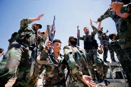 FILE PHOTO: Syrian army soldiers gesture as they hold their weapons in Quneitra, Syria, July 27, 2018. REUTERS/Omar Sanadiki/File Photo