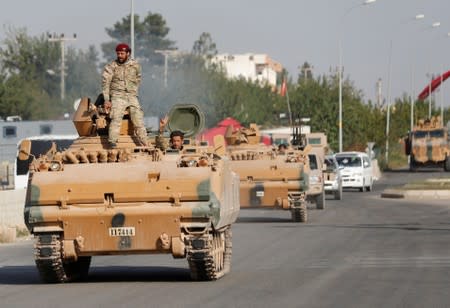 Members of Syrian National Army, known as Free Syrian Army, drive in an armored vehicle in the Turkish border town of Ceylanpinar